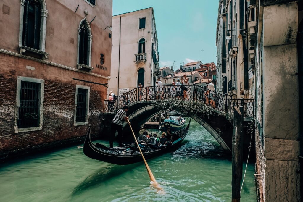 Gondola gliding under a picturesque bridge in Venice, capturing essence of urban Venetian waterways.